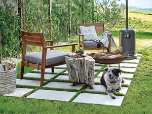 Outdoor armchairs on pavers next to a firepit and gas heater
