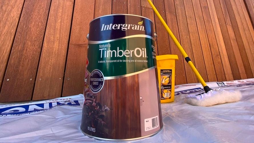 Timber oil container in front of timber fence.