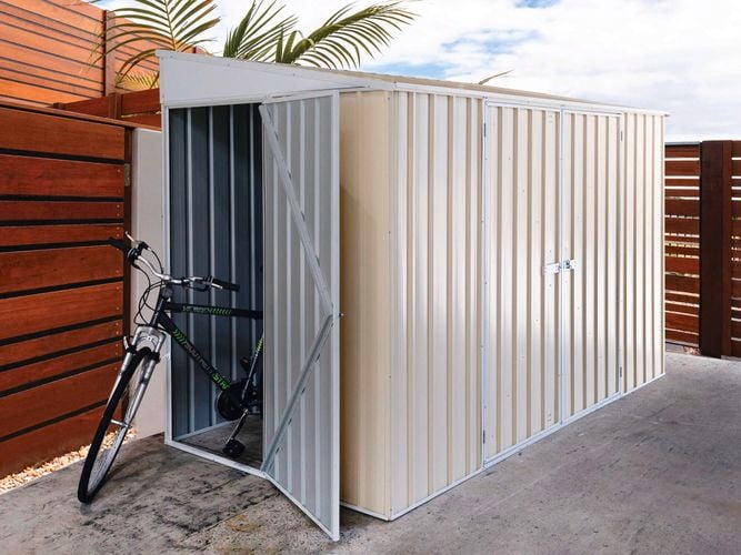 A cream shed with the bike at the front.