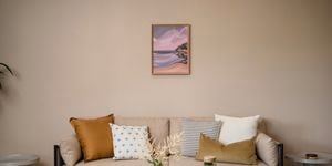 Lounge room with a couch with cushions on it, a picture hanging on the wall and a coffee table in it