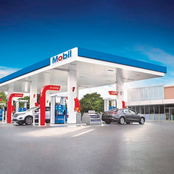Mobil petrol stats with two cars parked in it.