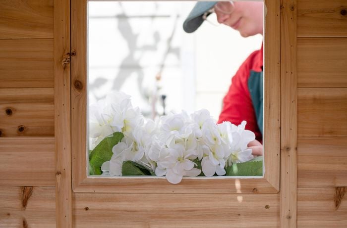 A Bunnings team member tending to a flower planter in the window of a cubby house