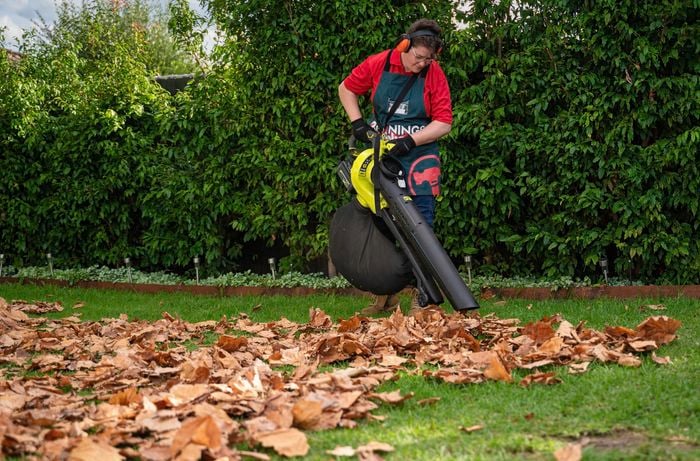 A person collecting leave and litter using a blower vacuum.