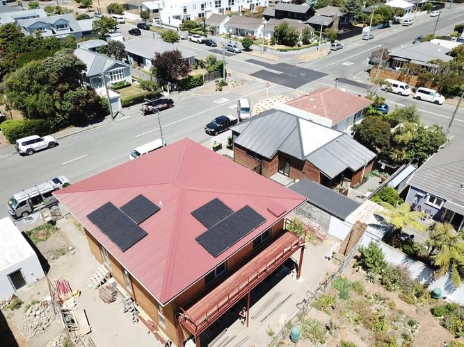 Black solar panels on top of a red roof of a house.