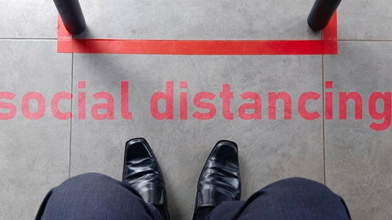 A person standing clear of a red line on the ground, with the caption 'social distancing'
