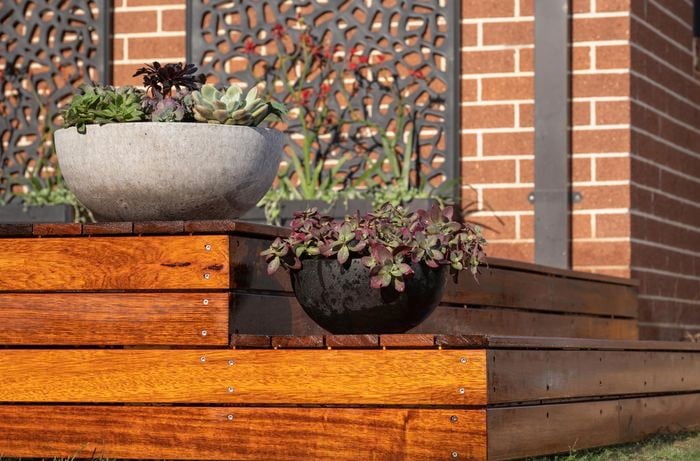 Wooden decking outside a house with plants and garden panels