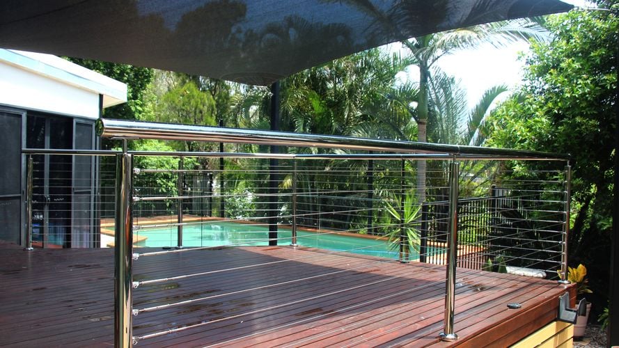 A metal deck railing with a pool in the background