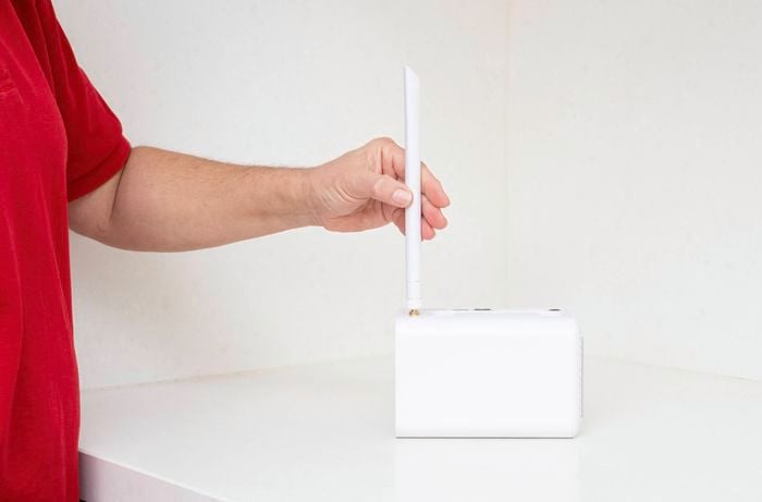A person is attaching an antenna to a Swann security system hub to maintain a strong connection between the hub and your wireless cameras.