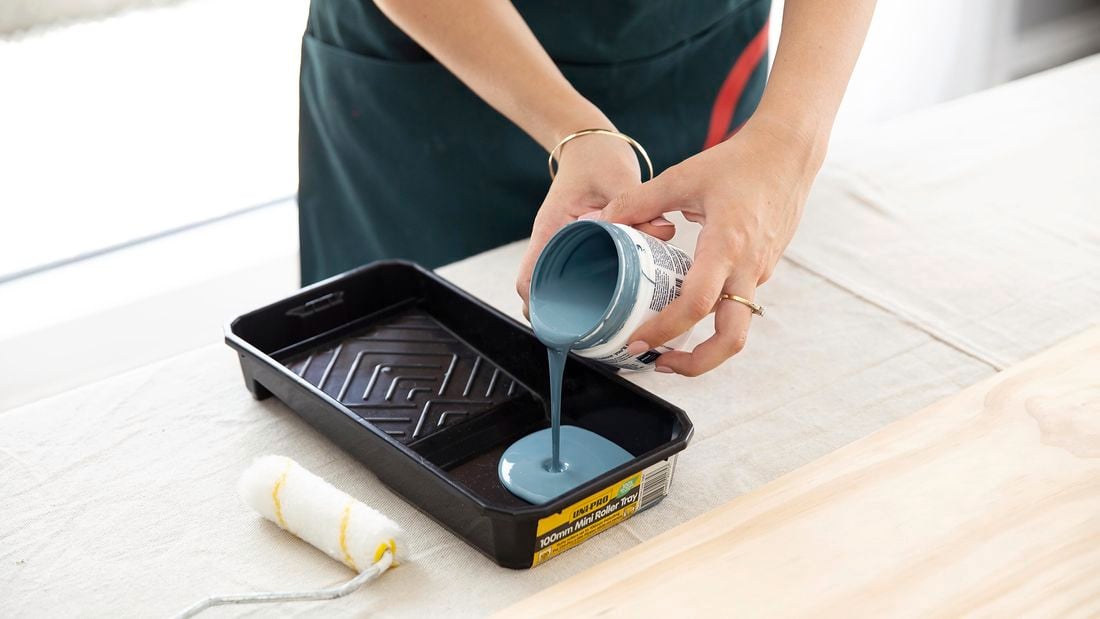 Pouring paint out of a paint pot into a paint tray