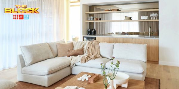 Contemporary living room featuring a large cream sectional sofa, timber coffee table and built-in timber cabinetry with open shelving.