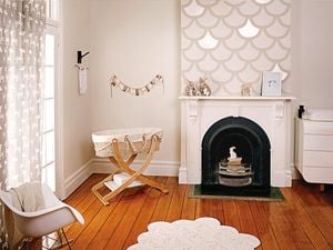 A nursery with a wooden cot, wooden floorboards, a cot and a fireplace. 