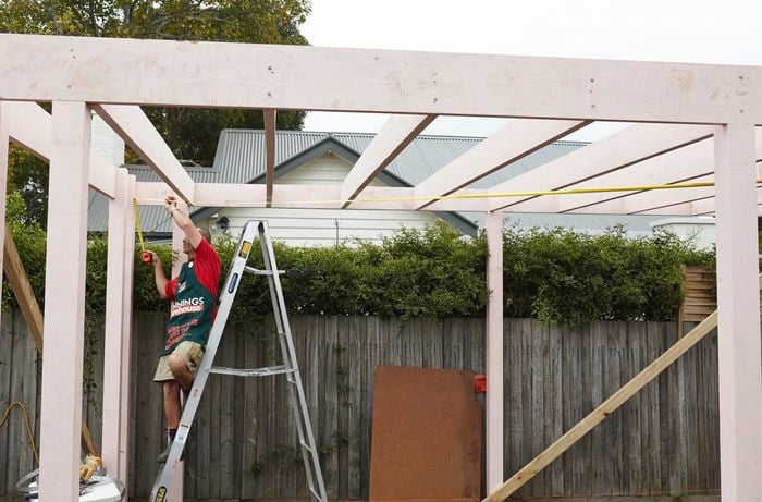 Person measuring a car port.