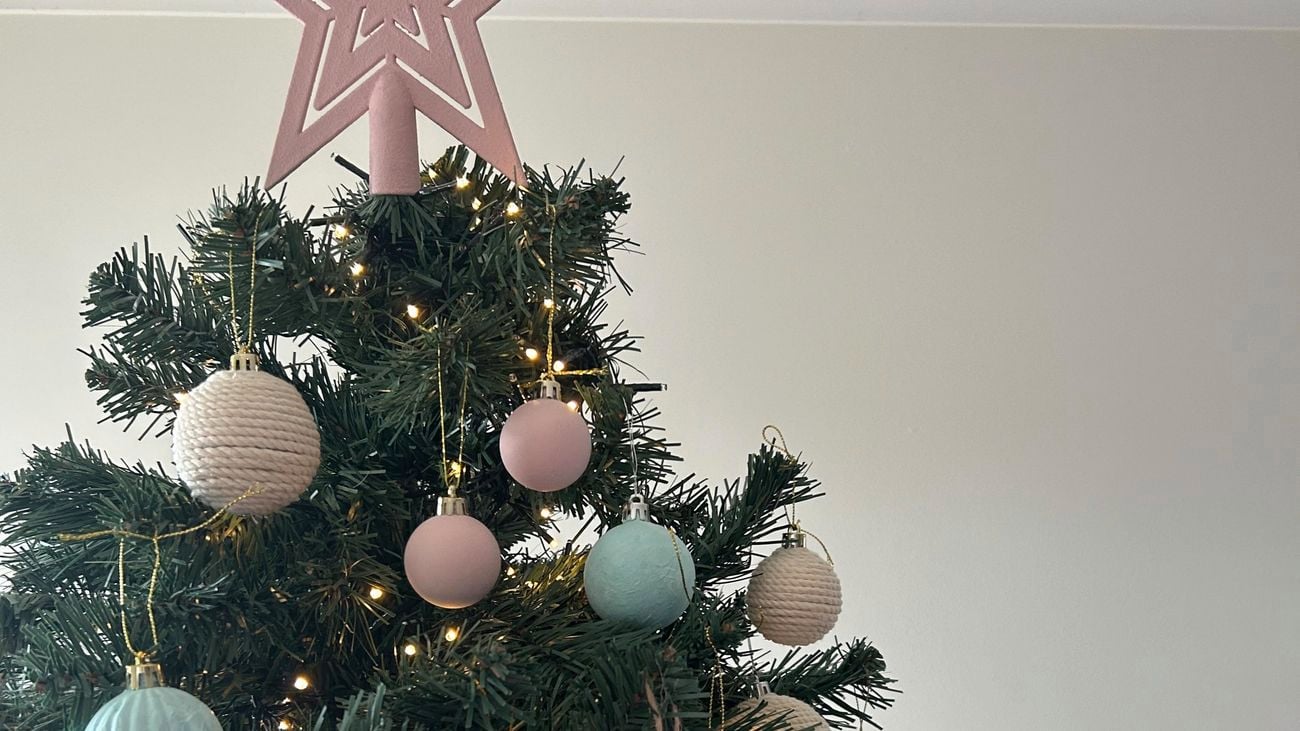 Christmas tree decorated with pastel pink, blue and cream baubles. A pastel pink star is placed at the top of the tree.