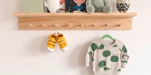 A floating timber shelf with books and toys above a green chest of drawers