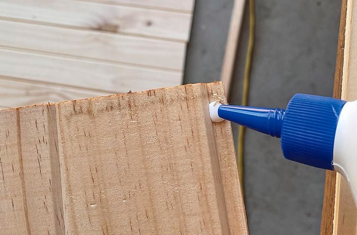 A person applies glue to a piece of pine