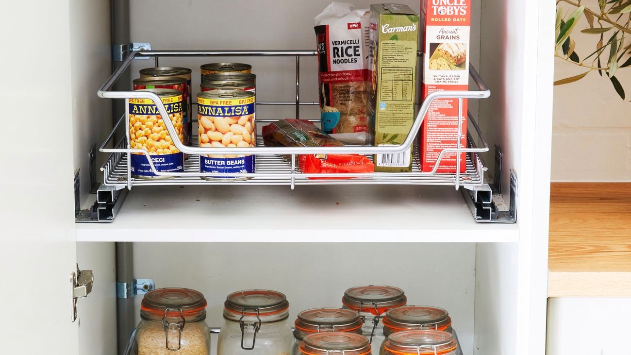 Close up image of pantry with metal pullout baskets carrying jars of spices and a bowl of vegetables
