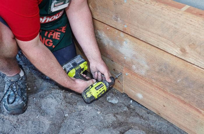 Person drilling bottom sleeper to support post.
