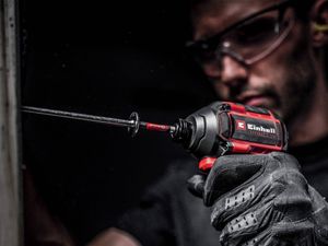 Close-up of a tradesperson using a cordless drill on a work surface.
