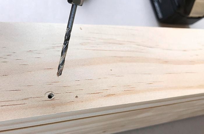 Holes being drilled into a coat rack to add a shelf to the top