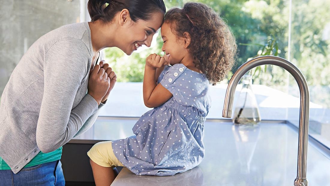 Mother and her daughter sit in the kitchen.