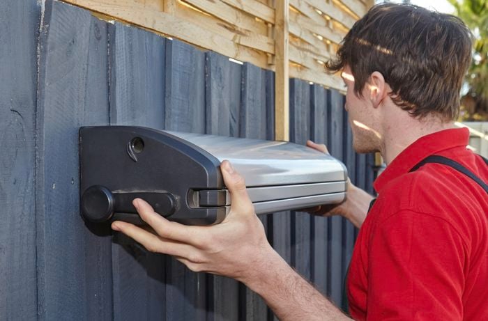 A Bunnings team member attaching the clothesline to the fence.