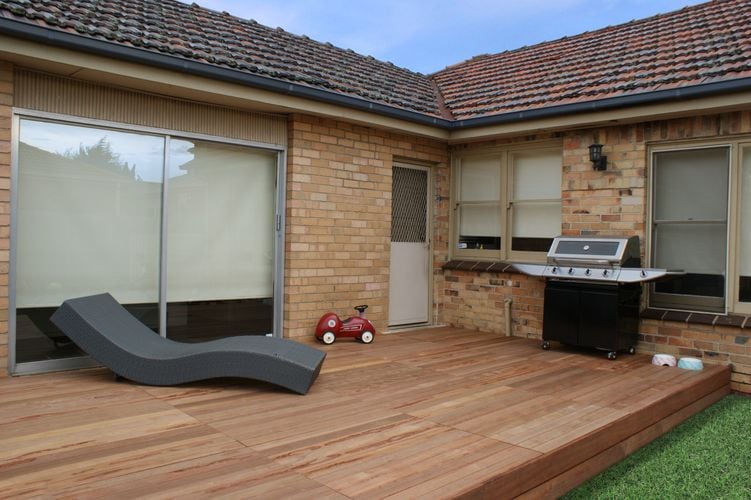 A deck at a backdoor with barbecue and modern deckchair