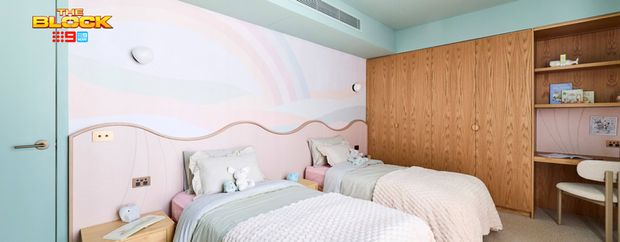 Contemporary twin bedroom featuring pastel bedding, a curved pink feature wall, timber wardrobes and a built-in study desk.