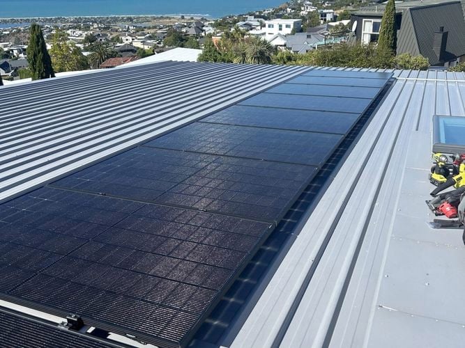 Black Solar panels on a grey roof of a building.