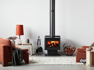 Loungroom setting with an indoor fire pit with a circular wood holder next to it and armchairs either side