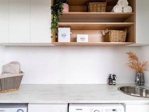 A laundry with a marble white benchtop with a basin in it, a dryer and washing machine in it.