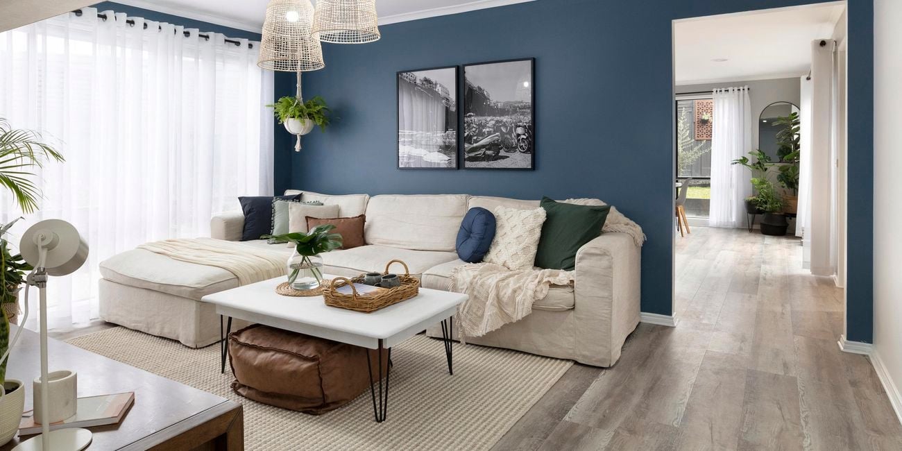 Living room with blue walls, white couch and coffee table, and indoor plants.