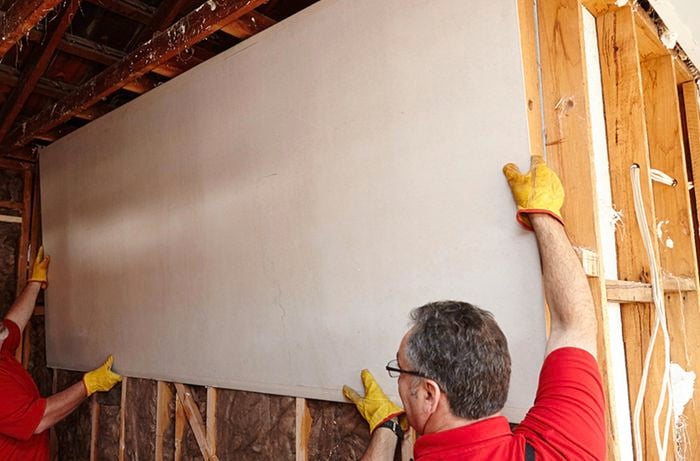 A top panel of villaboard being secured into place on a bathroom wall