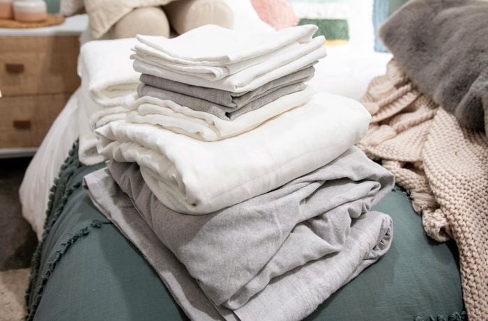 Stack of bed linen sitting on a bed