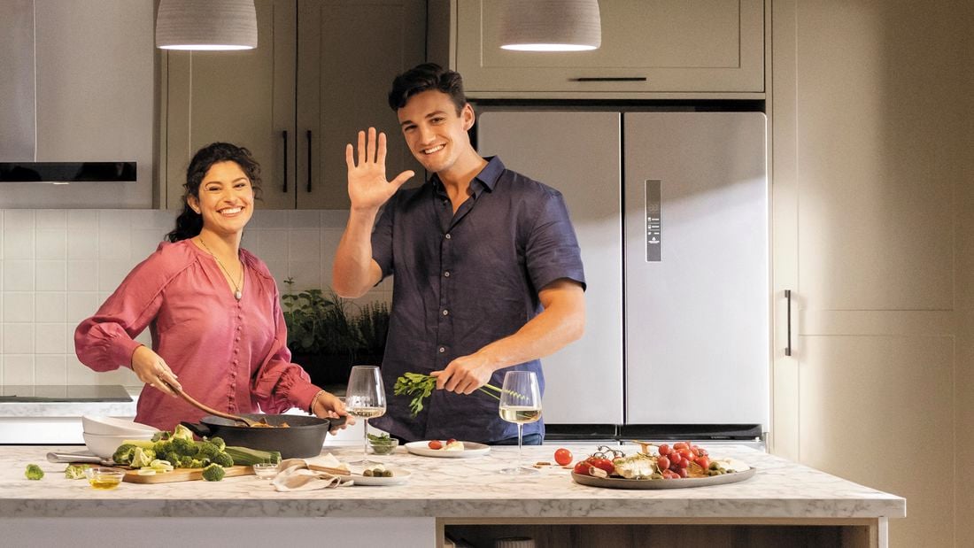 Man and woman standing in a kitchen facing at camera.