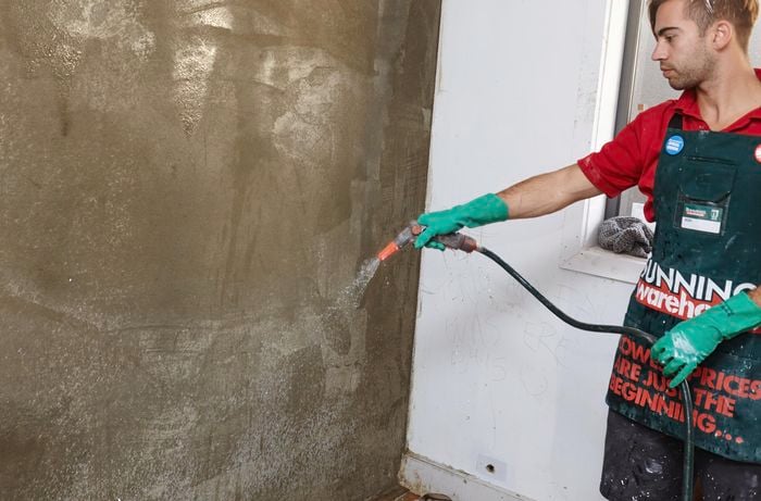 An indoor wall being hosed down before plaster is applied