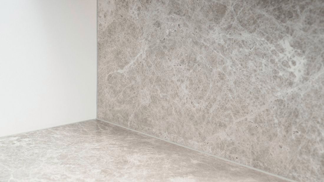 Finished silicone seal neatly applied along the joint between a stone-look benchtop and matching splashback, creating a clean, continuous finish in the corner of the installation.