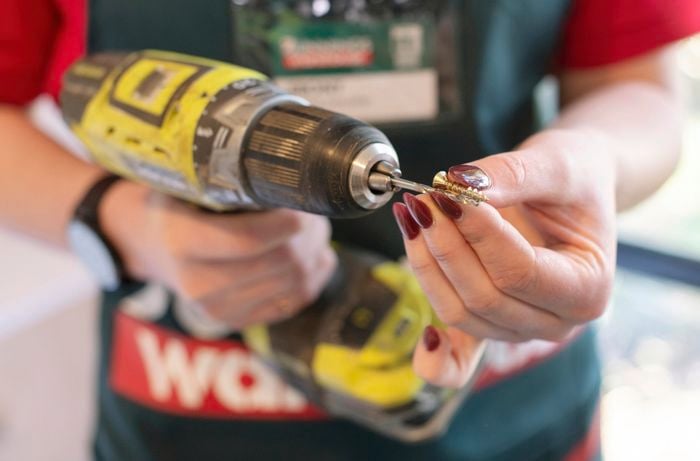 A person comparing the size of a drill bit and a screw