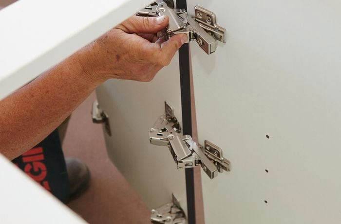 Person attaching door to cabinet