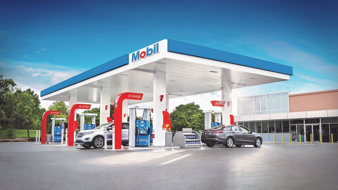 Mobil petrol stats with two cars parked in it.