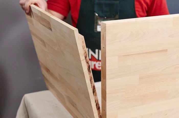Person placing side of timber sofa lounge against base.