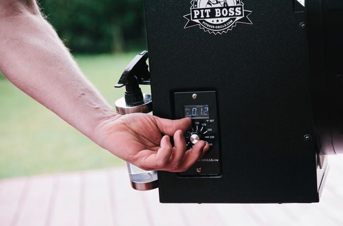 Person setting the temperature on a pellet smoker