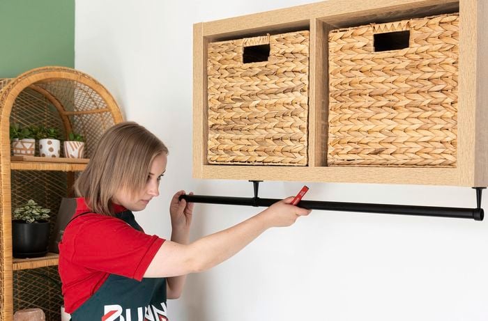 Person feeding rod into brackets for clothes rail