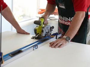 Person cutting a laminate benchtop with a saw.