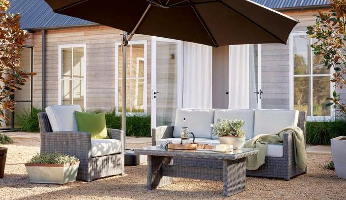 Backyard with an Outdoor Umbrella and outdoor furniture next to Pot plants.