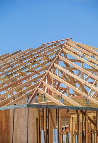 A house under construction with exposed wooden roofing trusses