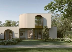 Modern house with curved facade, arched windows, lush garden and lawn.