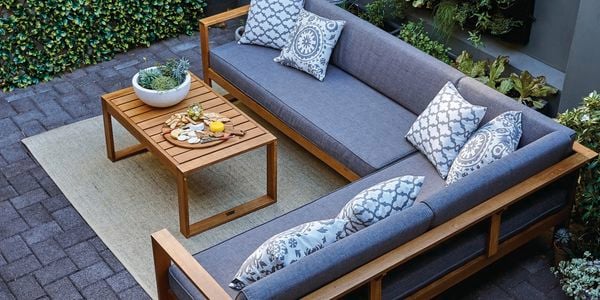 A tidy backyard with grey outdoor sofa setting and timber coffee table 