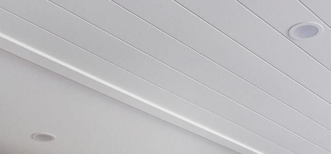 Close up of a white timber panelled ceiling with downlights 
