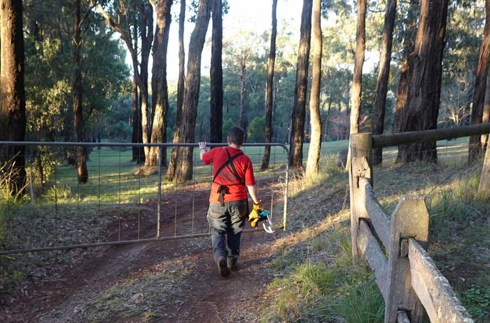 A person opening a gate on a bush property