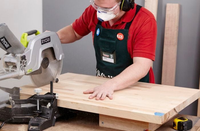 Person using circular saw to cut piece of timber to length.